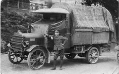 an old black and white photo of a man standing next to a truck