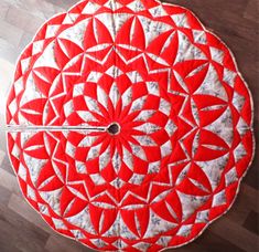 a red and white round table cloth on top of a wooden floor with a clock in the center