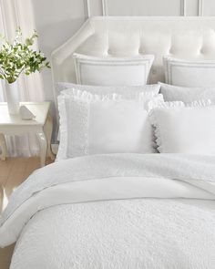 a bed with white sheets and pillows in a room