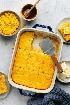 corn casserole in a baking dish with butter and other dishes around it on a table