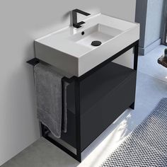 a white sink sitting under a bathroom mirror next to a black cabinet and towel dispenser