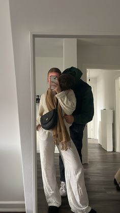 a man and woman taking a selfie in an empty room with wood flooring