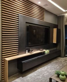 a living room with a large television on the wall and wooden slats behind it