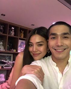 a man and woman taking a selfie in front of a shelf full of jewelry