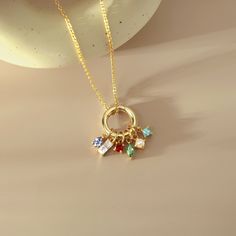 a gold plated necklace with four charms hanging from it's center, on a beige surface