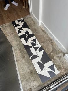 a black and white tiled floor next to a doorway with a dog looking at it