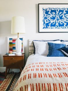 a bedroom with a bed, lamp and pictures on the wall