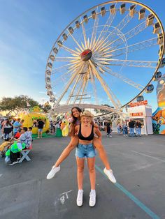 two women are posing in front of a ferris wheel