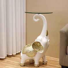 an elephant shaped glass table with gold accents on it's legs and the base