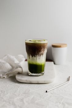 a green drink sitting on top of a white plate