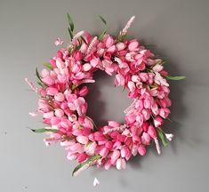 a wreath with pink flowers hanging on the wall next to a gray wall and grey background