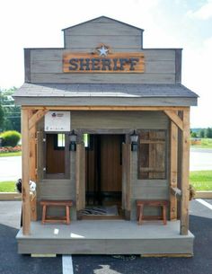 a small building with two benches in front of it and a sheriff sign above the door