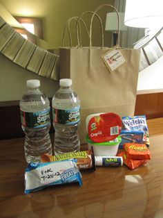 two bottles of water sitting on top of a wooden table next to snacks and candy