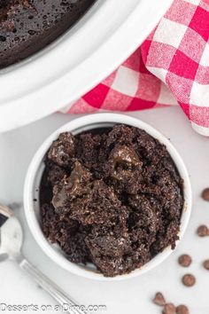 a white bowl filled with chocolate cake next to a red and white checkered napkin