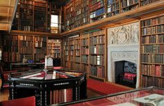 an old library with many bookshelves and tables in the center, along with a fireplace