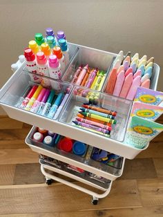 a cart filled with lots of different colored crayons and markers on top of a hard wood floor