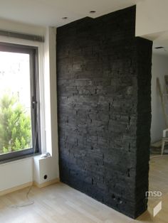 an empty room with a black brick wall next to a window and a radiator