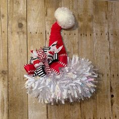 a red and white santa hat on top of a pile of shredded paper with a pom pom attached to it