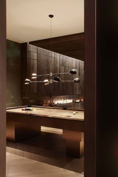 a pool table in the middle of a room with lights hanging from it's ceiling