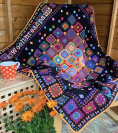 a crocheted blanket sitting on top of a table next to flowers and a cup