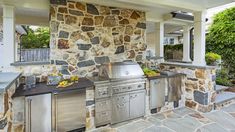 an outdoor kitchen with stainless steel appliances and stone walls