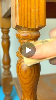 a person is holding a piece of paper under a wooden table with a hand on it