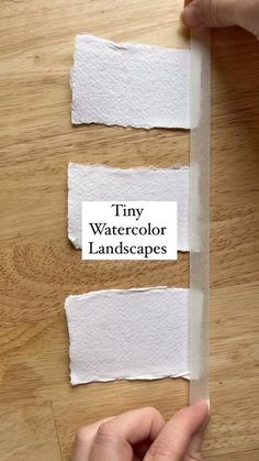 someone is cutting out pieces of white paper with the words tiny watercolor landscapes on them