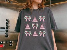 Get festive in style with our *Retro Christmas Coquette Bow Shirt*! 🎀🎅 This adorable tee features a cute retro Santa design, perfect for adding charm to your holiday wardrobe. Made from the ultra-soft Comfort Colors© fabric, it's cozy, durable, and ideal for layering during the Christmas season. The delicate coquette bow detail adds a chic touch, making this a go-to piece for all your holiday outings.  Whether you're sipping cocoa by the fire or heading to a holiday party, this cute Christmas tee will have you looking fabulous and festive. For an oversized fit, **go two sizes up** for that perfect cozy vibe! 🎄✨  Looking for the perfect Christmas gift for a friend or yourself? This retro Santa tee is sure to spread holiday cheer. **All sales are final** since each shirt is made to order, Retro Christmas Shirt, Santa Tee, Christmas Coquette, Retro Santa, Bow Shirt, Cute Santa, Bow Shirts, Coquette Bow, Women Christmas