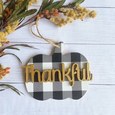 a thanksgiving ornament with the word grateful hanging from it's side next to some flowers