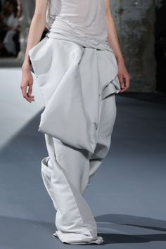 a model walks down the runway in white clothing