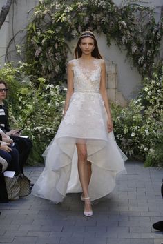 a woman walking down a runway wearing a white dress