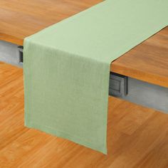 a green table runner is on top of a wooden table with a metal rail and wood flooring