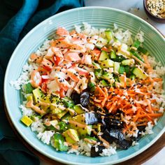 a blue bowl filled with rice and vegetables