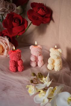 three crocheted teddy bears sitting next to each other on a table with flowers