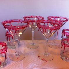 six wine glasses with red paint on them sitting on a table