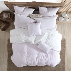 an overhead view of a bed with white linens and pillows on top of it