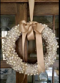 a wreath with pearls and a bow hanging on a door