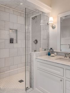 a bathroom with a walk in shower next to a double sink vanity and white cabinets