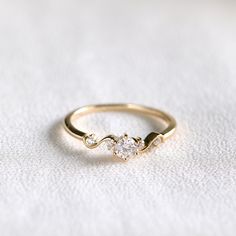 a gold ring with two diamonds on it sitting on a white cloth covered tablecloth