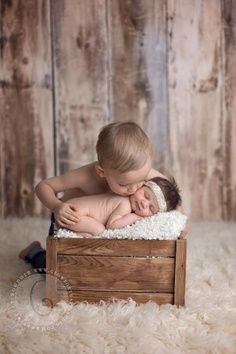 a baby is laying in a wooden crate with his head on its mother's chest