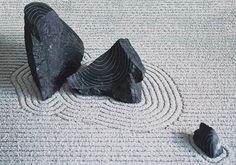 two black rocks sitting next to each other on top of a white carpeted floor