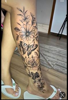 a woman's leg with flowers and butterflies on it