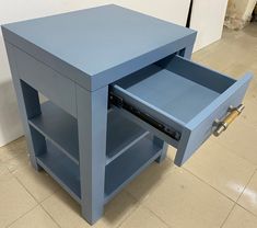 a blue table with an open drawer on the bottom and one drawer opened in front