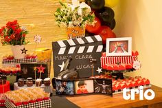 a table topped with cakes and cupcakes next to a movie clapper board