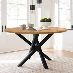 a wooden table with black legs and a bowl of green apples on the table top