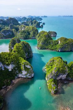 an aerial view of several small islands in the water with green trees and rocks around them