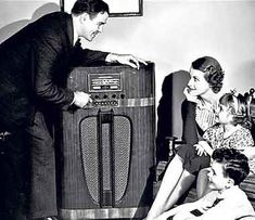 an old black and white photo of two people with a radio in front of them