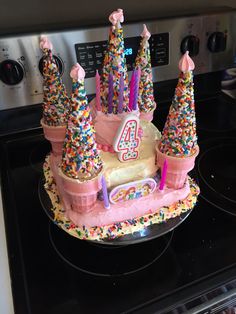 a birthday cake with candles and sprinkles on it sitting on top of a stove