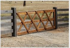 a wooden gate in the middle of a dirt field