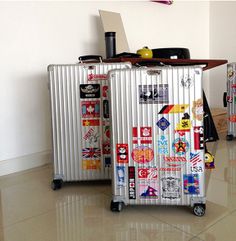 two suitcases with stickers on them sitting next to each other in a room